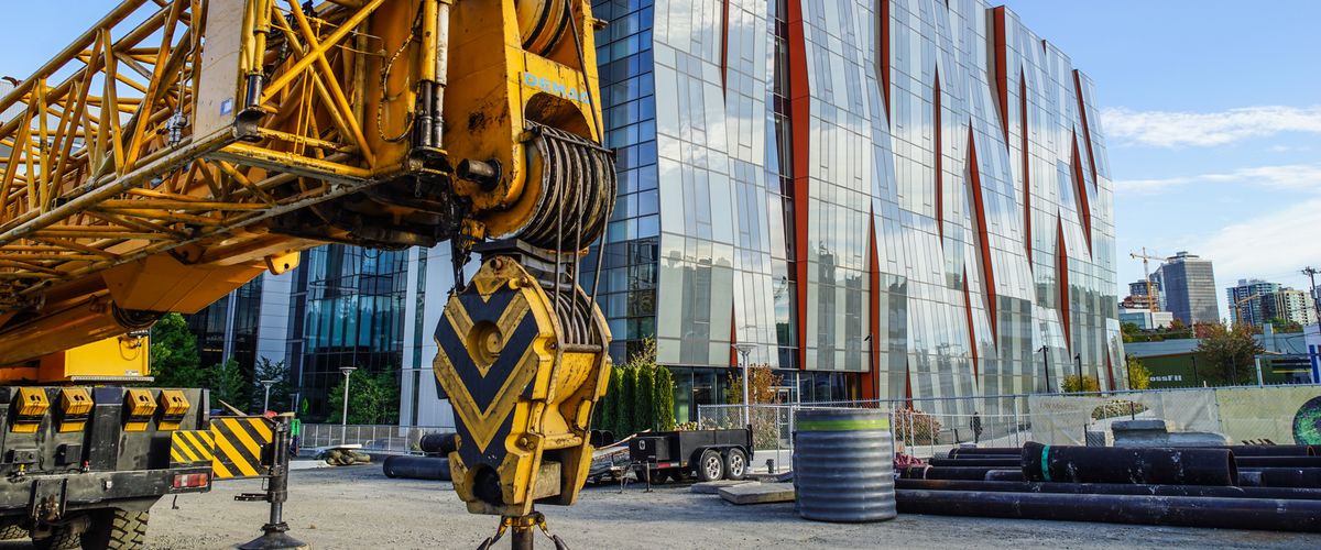 A crane hook in front of a new glass office building