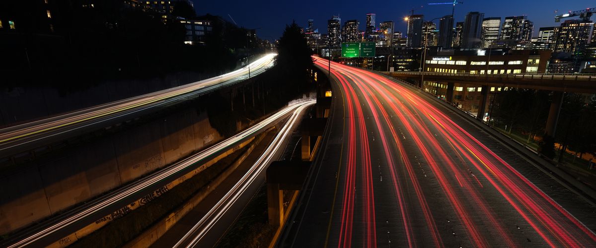 Light trails from freeway traffic below a city skyline at blue hour