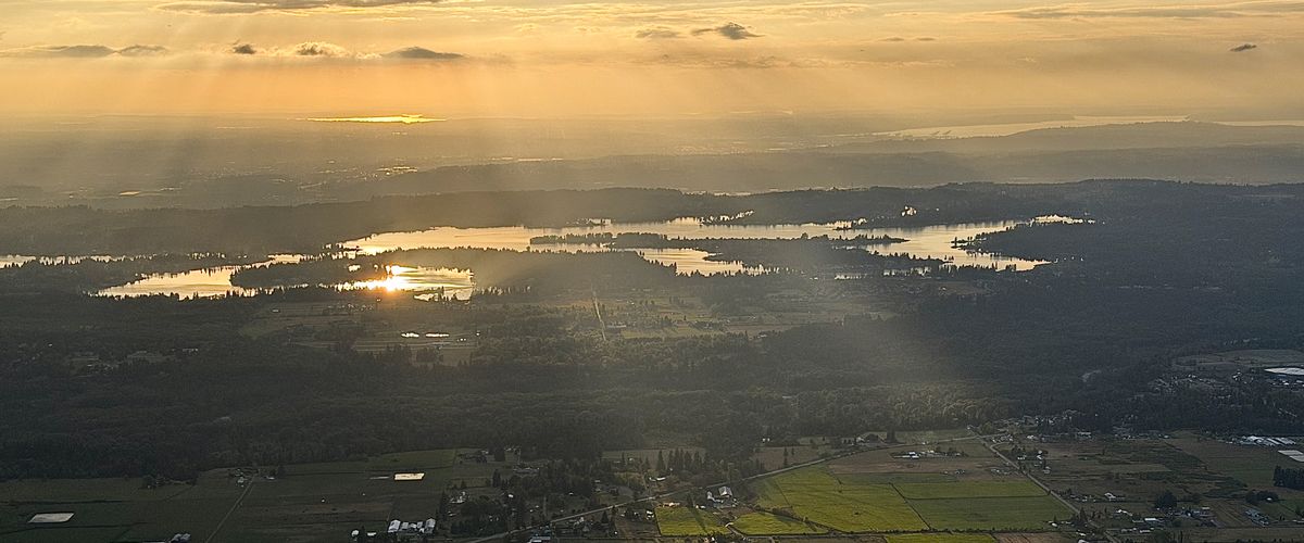 Evening light breaking through cloud over lakes and farmland, seen from above